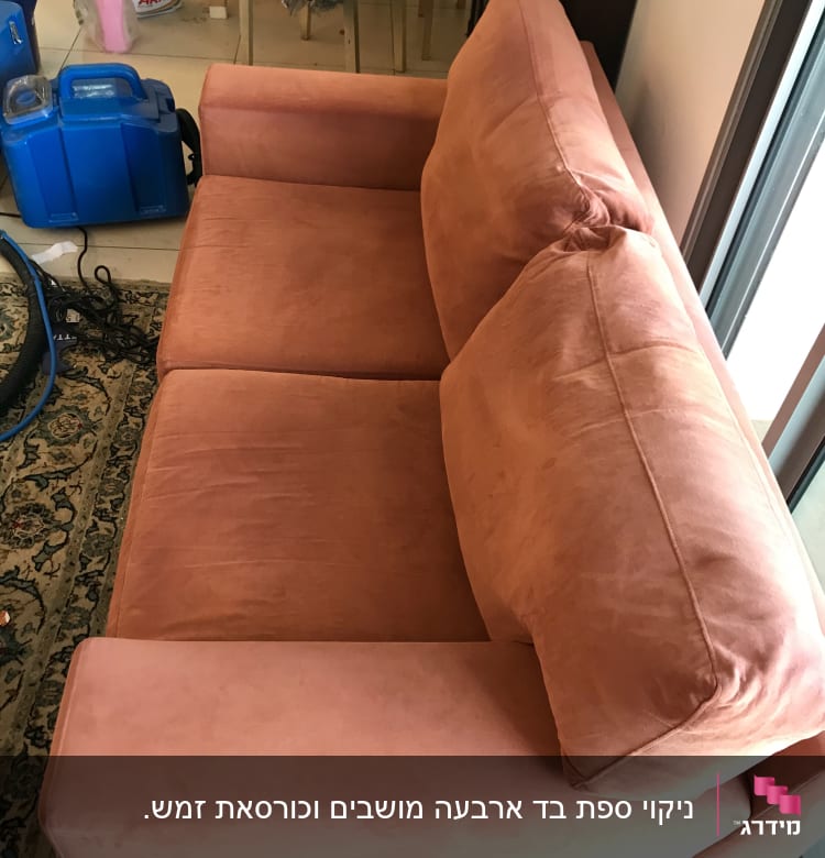 ספה כתומה עם מכונת ניקוי כחולה ליד